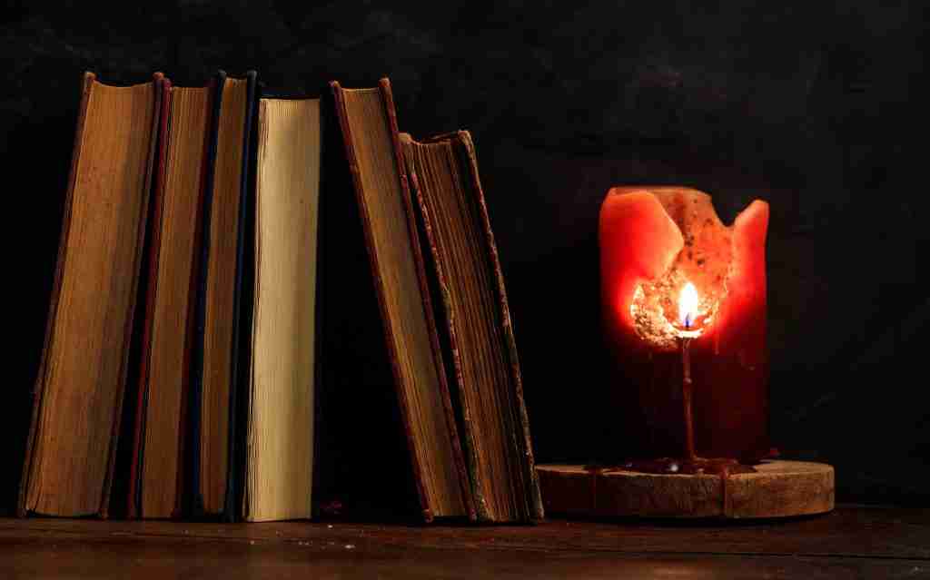 vintage books and candle on dark background 2022 12 16 12 18 20 utc